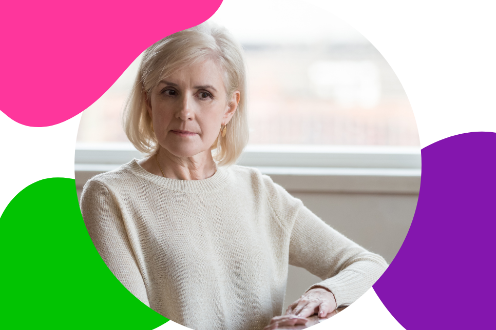 ältere Frau mit grau-blonden Haaren sitzt nachdenklich an einem Tisch und denkt darüber nach, was Hashimoto bedeutet