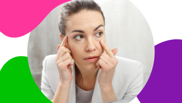 junge Frau mit braunen Haaren schaut sich im Spiegel ihre vergrößerten Augen an, welche ein Symptom von Morbus Basedow sind