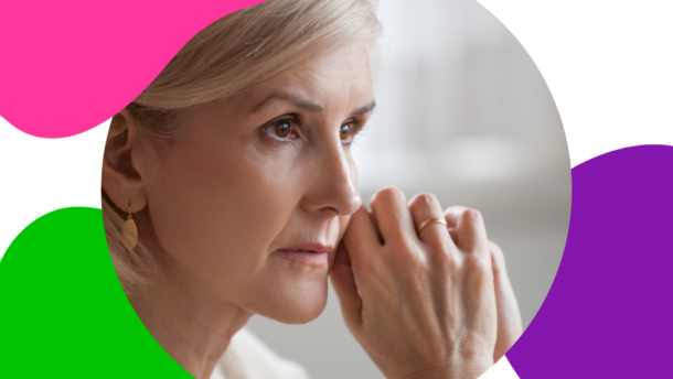 ältere Frau mit grau-blonden Haaren sitzt nachdenklich an einem Tisch und denkt darüber nach, wie sie trotz ihrer Schilddrüsenerkrankung den Ruhestand genießen kann