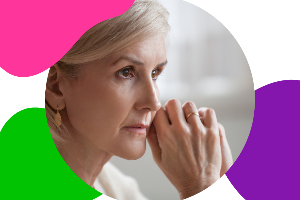 ältere Frau mit grau-blonden Haaren sitzt nachdenklich an einem Tisch und denkt darüber nach, wie sie trotz ihrer Schilddrüsenerkrankung den Ruhestand genießen kann